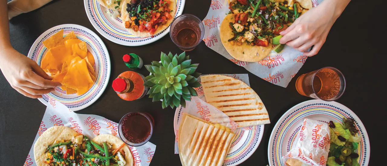 Siéntese alrededor de una mesa al aire libre en El Loco Fresh o pide tu comida para llevar